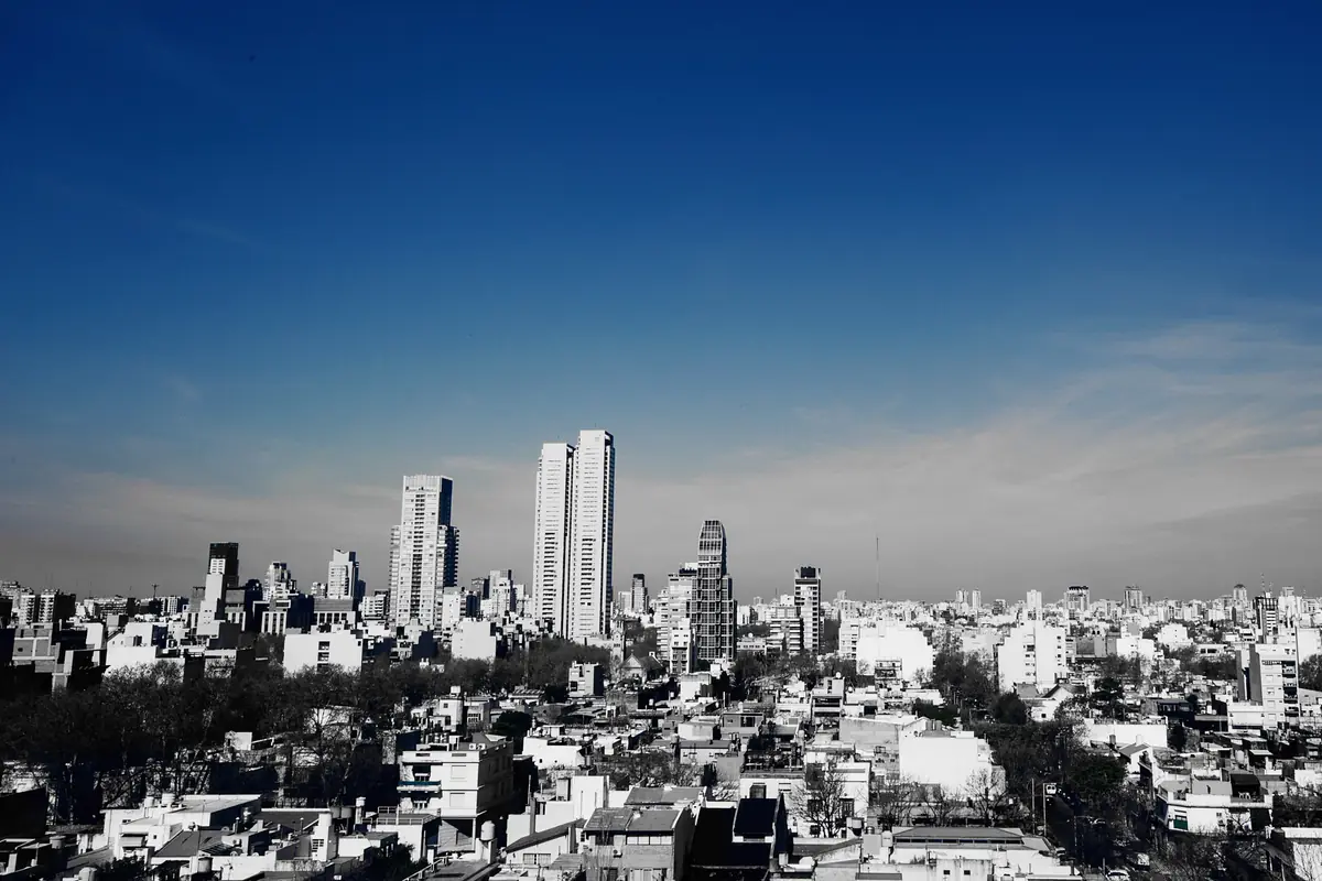 Palermo Hollywood'un alçak çatılarına yayılan geniş bir manzara; derin mavi gökyüzü altında yükselen uzun apartman kuleleri